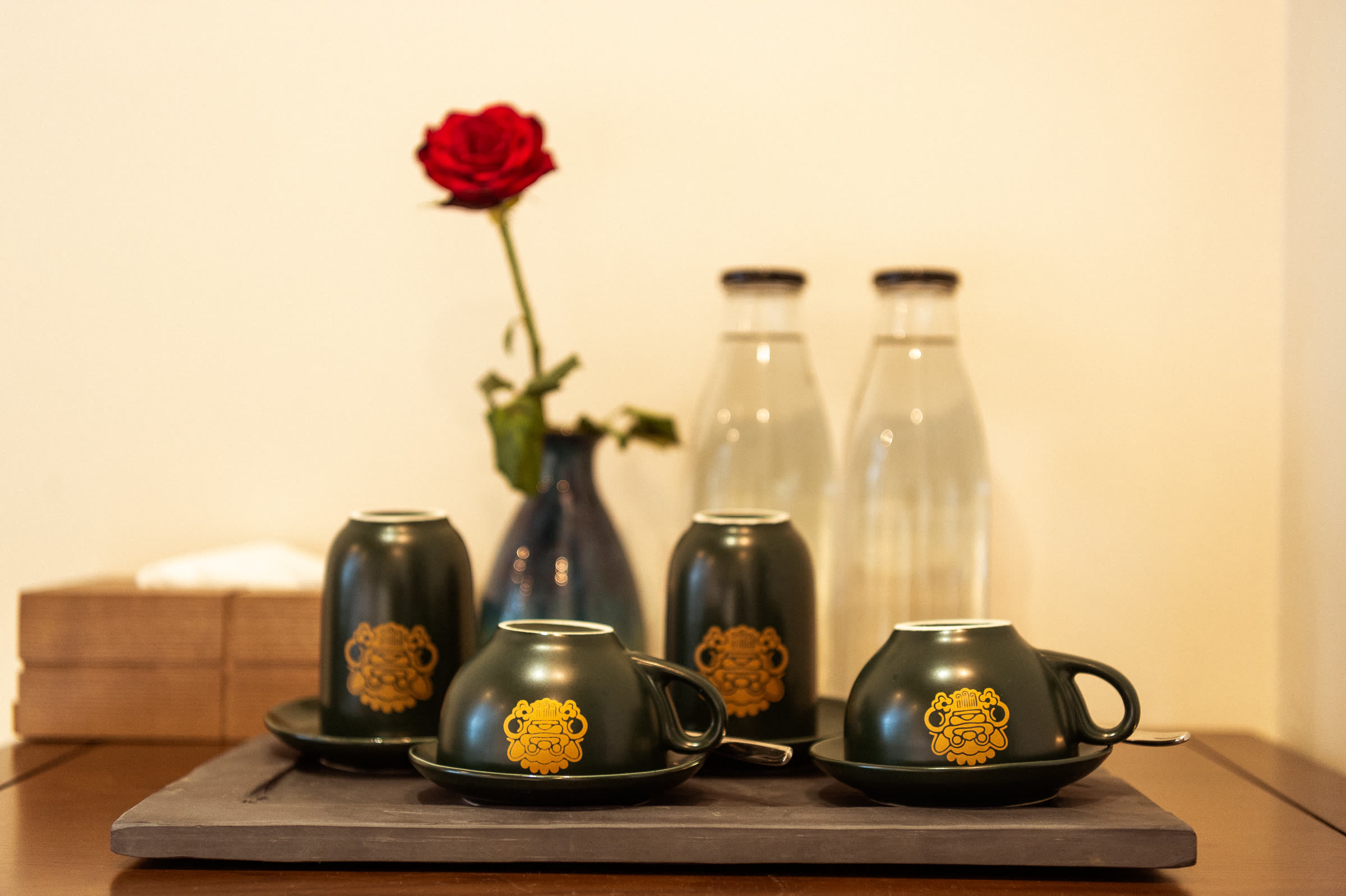 The gold-stamped Nghê tea service, water flasks and a red rose in a guest room at Nghê Prana
