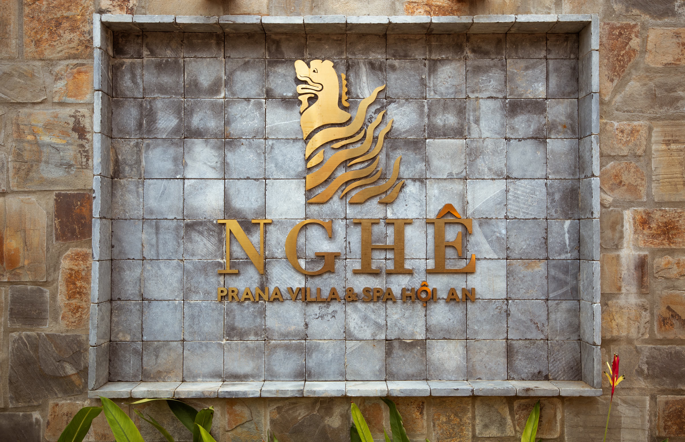 The gold Nghê Prana emblem on the stone entrance wall in Hội An