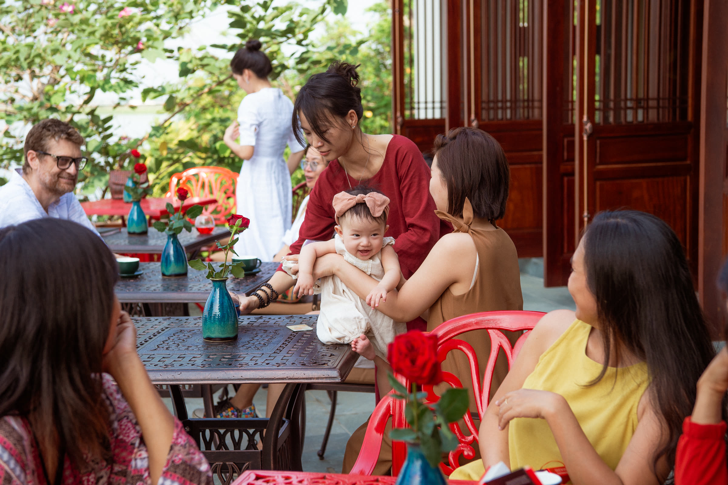 Guests at a long table on the riverside terrace at Nghê Prana, Hội An
