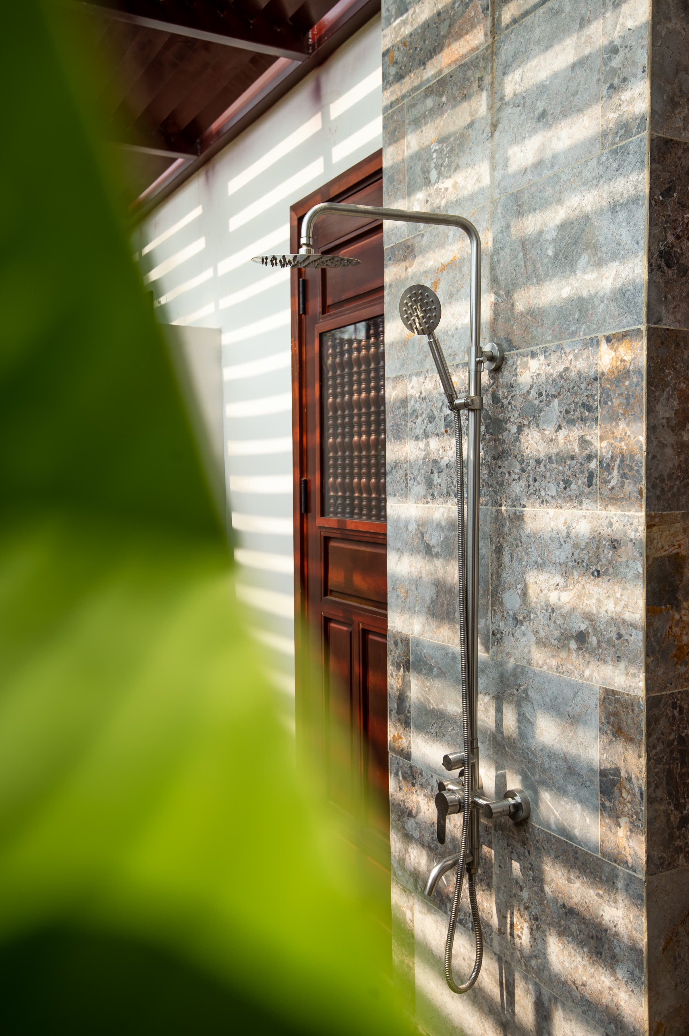 The Junior Suite's open-air rain shower against a stone wall at Nghê Prana