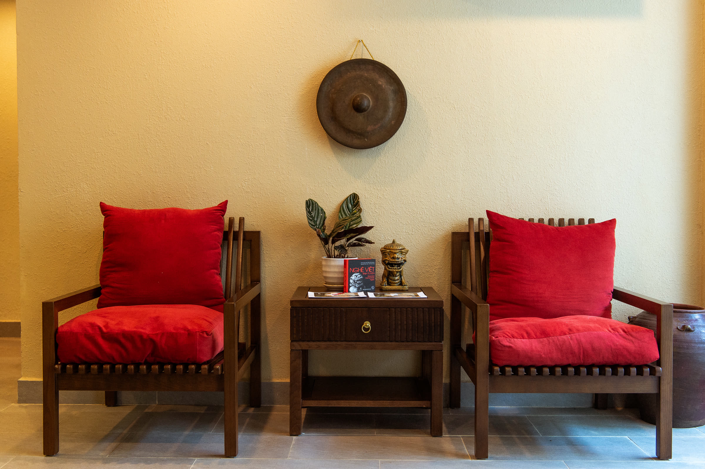 Two red armchairs and a low table in the quiet lounge at Nghê Prana spa, Hội An